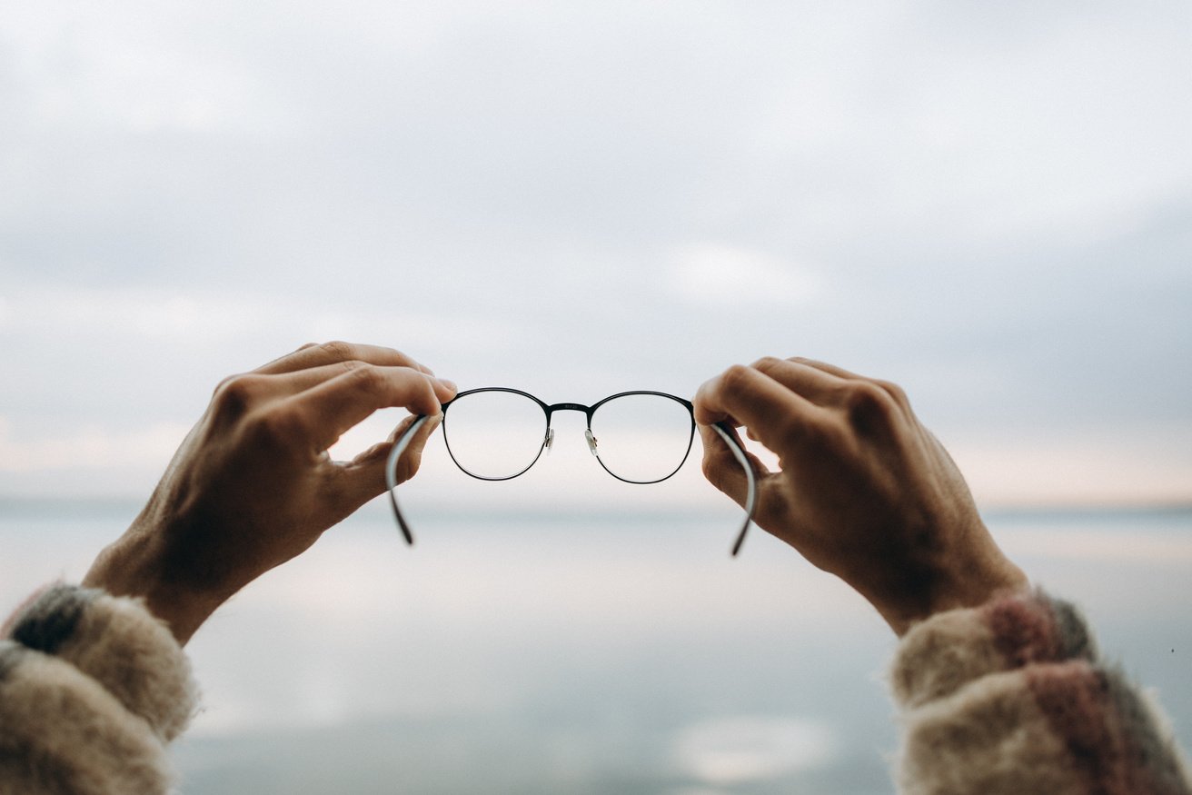  A Person Holding a Pair of Black Framed Eyeglasses